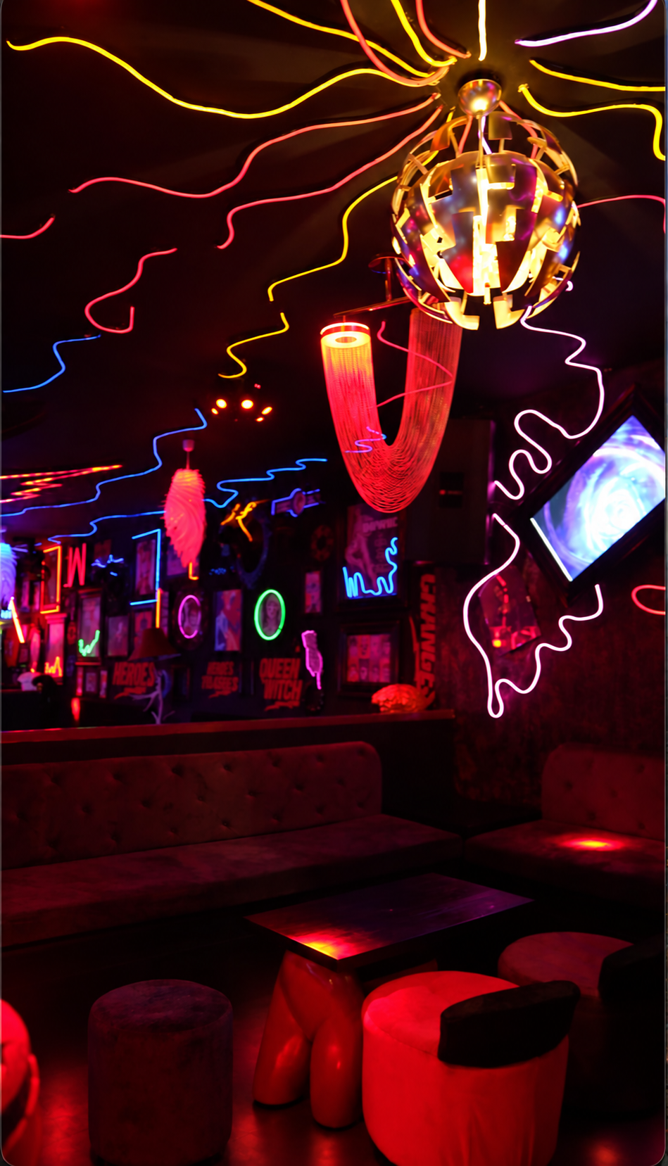 Sofá bajo una lámpara escultórica y luces de colores
