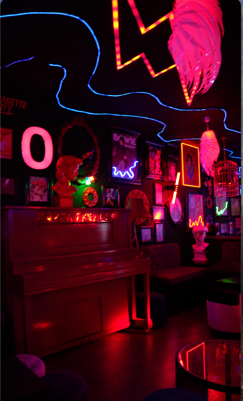 Piano de Bowie rodeado de cuadros y luces de neón